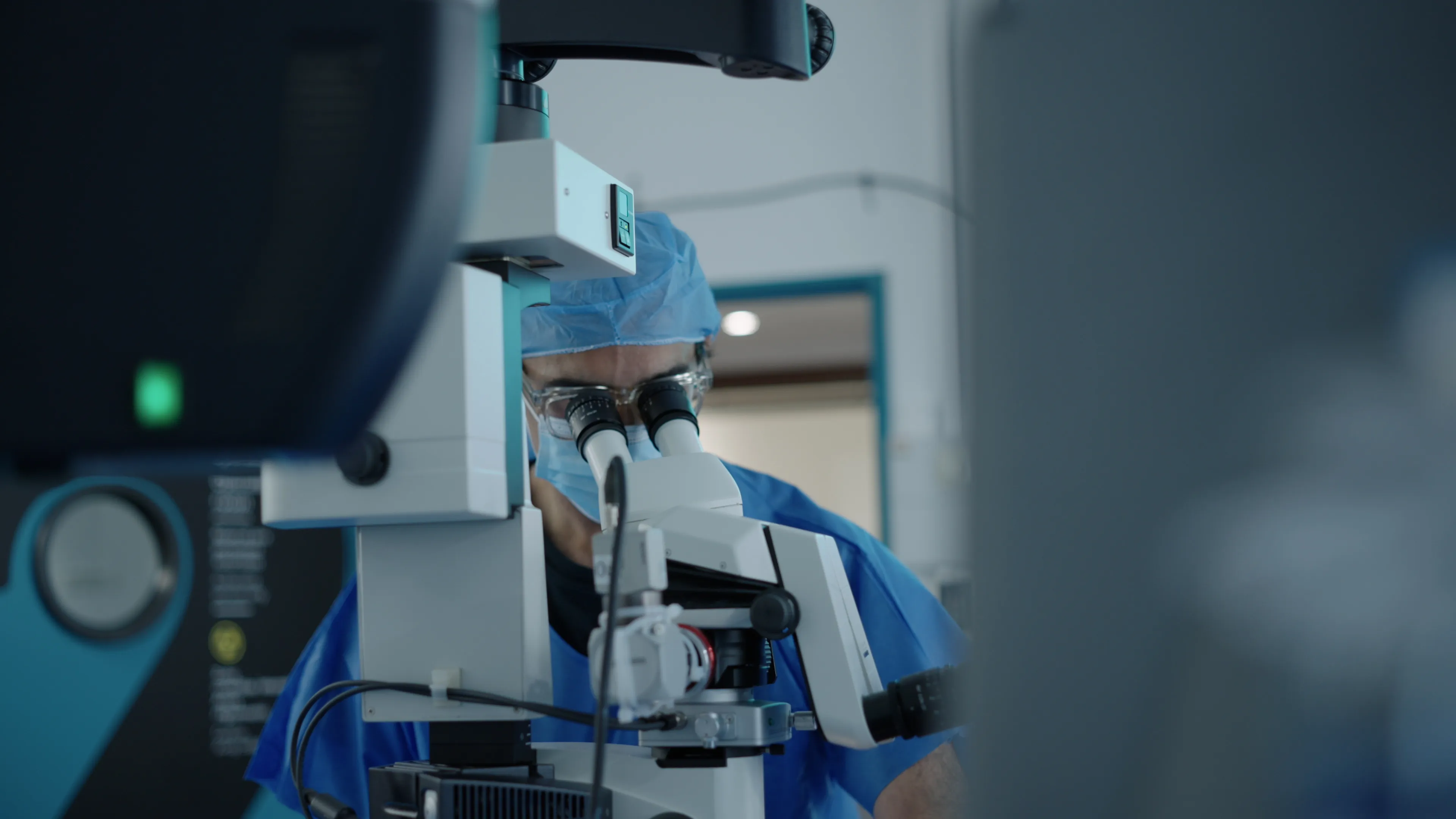 Dr. Muqit looking through a microscope during surgery.